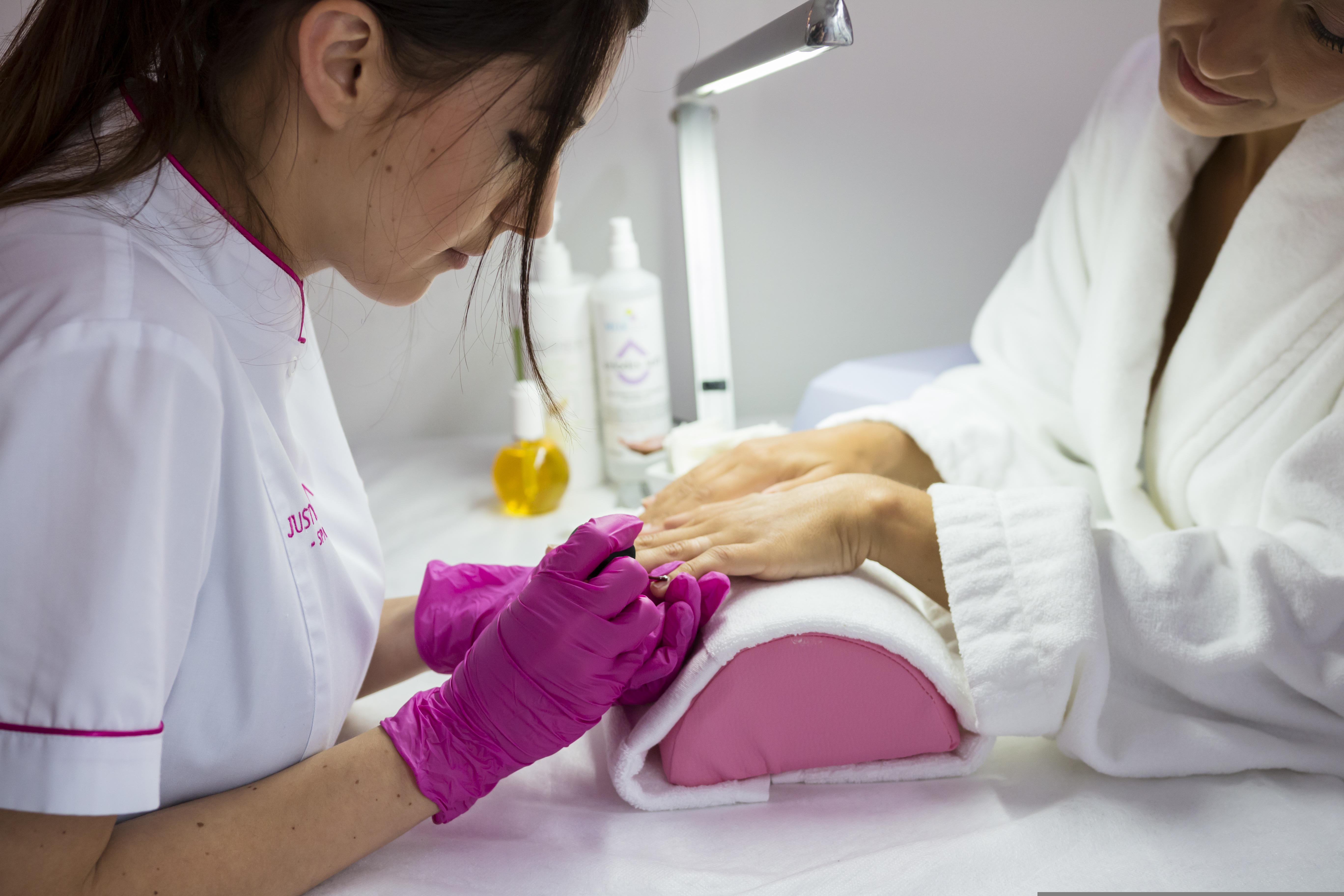 Beautician performing manicure in a bright studio