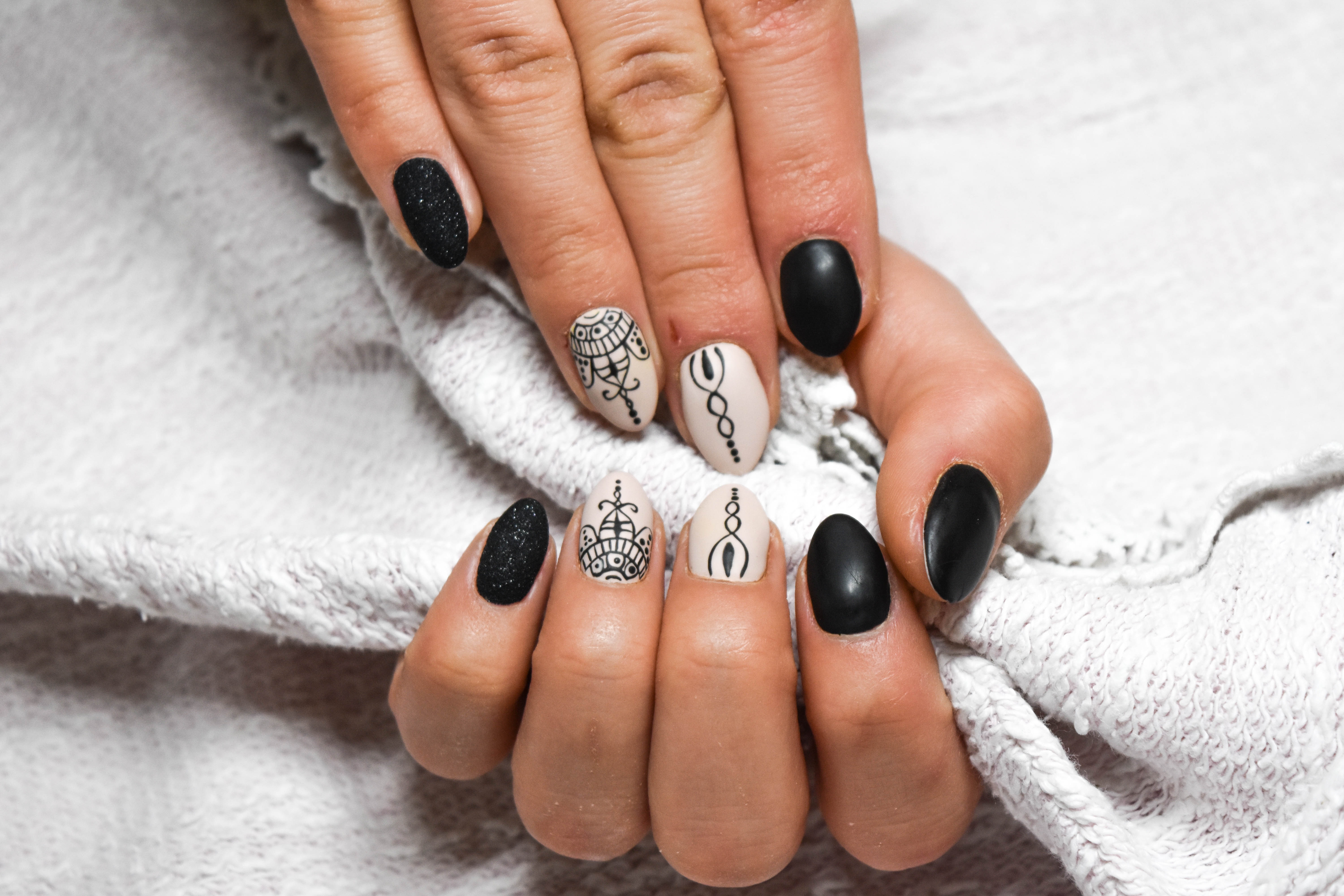 Close-up nail art with matte black and nude designs